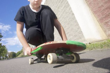 Bir kaykay ile bir genç. Bir kaykay üzerinde oturur.