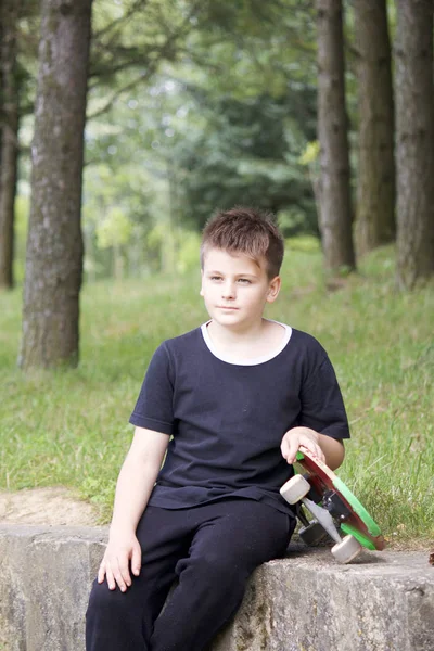 Bir kaykay ile bir genç. Bir paten elinde tutan.