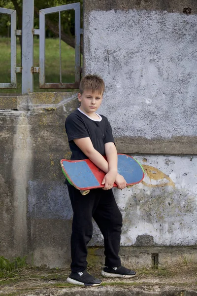 Bir kaykay ile bir genç. Bir paten elinde tutan.