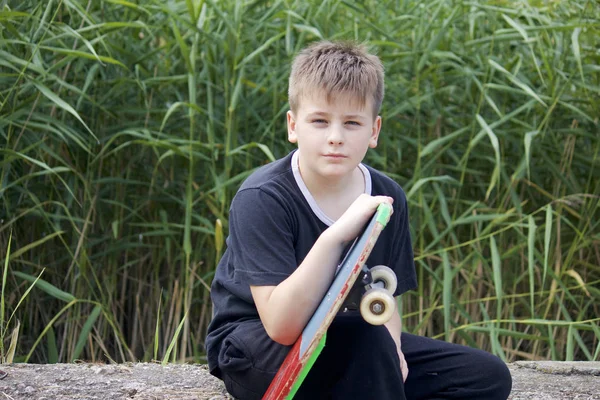 Bir kaykay ile bir genç. Bir paten elinde tutan.