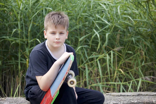 Bir kaykay ile bir genç. Bir paten elinde tutan.