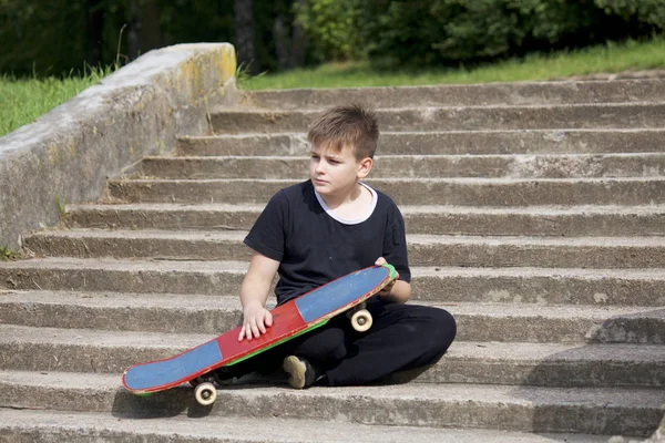 Adolescente Com Skate Senta Com Skate Contra Pano Fundo Uma — Fotografia de Stock