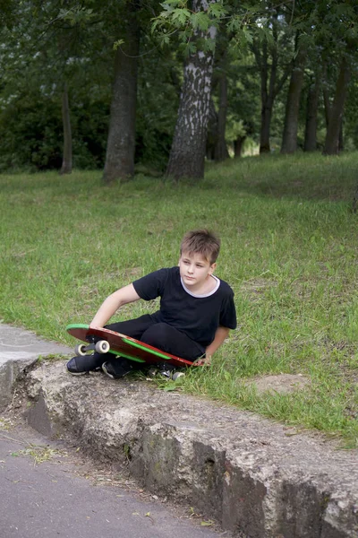 Bir kaykay ile bir genç. Bir paten elinde tutan.