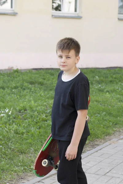 Bir kaykay ile bir genç. Bir paten elinde tutan.