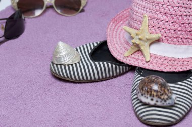Sahilde tatile. Güneş ve güneş gözlüğü koruma için şapka. Plaj Spor Ayakkabı, deniz yıldızı. Plaj havlusu arka planı.