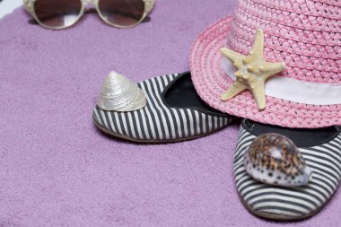 Sahilde tatile. Güneş ve güneş gözlüğü koruma için şapka. Plaj Spor Ayakkabı, deniz yıldızı. Plaj havlusu arka planı.