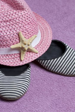 Sahilde tatile. Güneşten korunması için şapka. Plaj Spor Ayakkabı, deniz yıldızı. Plaj havlusu arka planı.