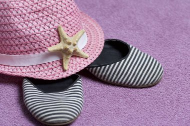 Sahilde tatile. Güneşten korunması için şapka. Plaj Spor Ayakkabı, deniz yıldızı. Plaj havlusu arka planı.