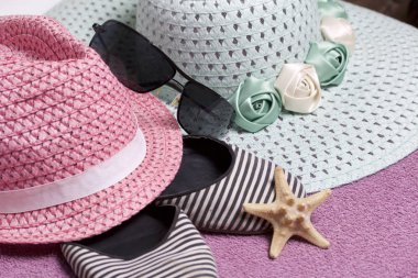 Sahilde tatile. Güneş ve güneş gözlüğü koruma için şapka. Plaj Spor Ayakkabı, deniz yıldızı. Plaj havlusu arka planı.