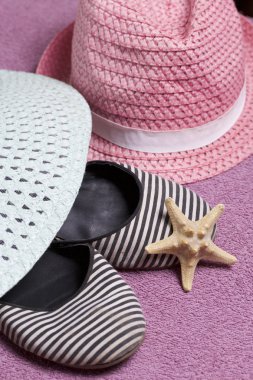 Sahilde tatile. Güneşten korunması için şapka. Plaj Spor Ayakkabı, deniz yıldızı. Plaj havlusu arka planı.