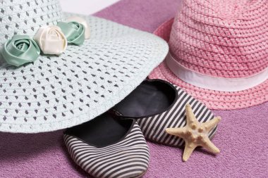Sahilde tatile. Güneşten korunması için şapka. Plaj Spor Ayakkabı, deniz yıldızı. Plaj havlusu arka planı.
