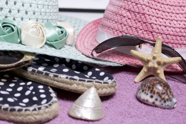 Sahilde tatile. Güneş ve güneş gözlüğü koruma için şapka. Plaj spor ayakkabıları. Deniz yıldızı ve deniz kabuklarını. Plaj havlusu arka planı.