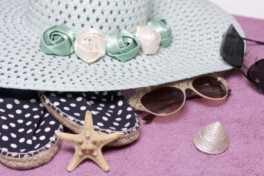 Sahilde tatile. Güneş ve güneş gözlüğü koruma için şapka. Plaj spor ayakkabıları. Deniz yıldızı ve deniz kabuklarını. Plaj havlusu arka planı.