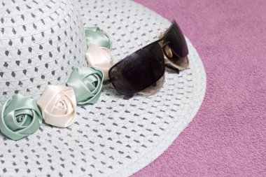 Sahilde tatile. Güneş ve güneş gözlüğü koruma için şapka. Plaj havlusu arka planı.