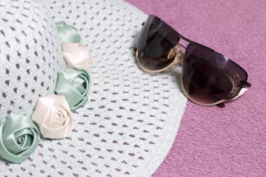 Sahilde tatile. Güneş ve güneş gözlüğü koruma için şapka. Plaj havlusu arka planı.