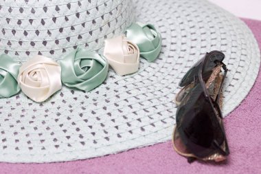 Sahilde tatile. Güneş ve güneş gözlüğü koruma için şapka. Plaj havlusu arka planı.