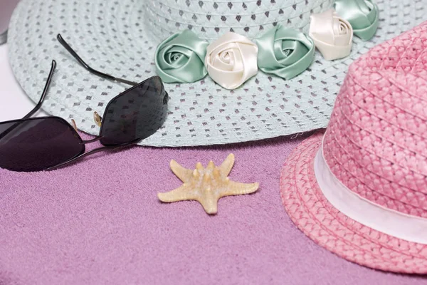 Sahilde tatile. Güneş ve güneş gözlüğü koruma için şapka. Plaj havlusu arka planı.