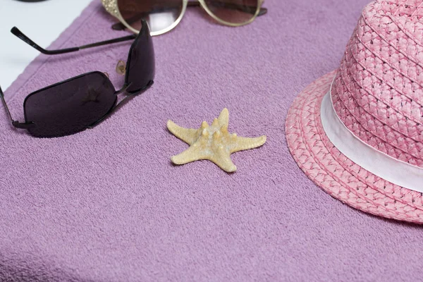 Sahilde tatile. Güneş ve güneş gözlüğü koruma için şapka. Plaj havlusu arka planı.