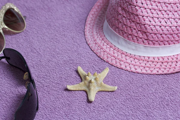 Sahilde tatile. Güneş ve güneş gözlüğü koruma için şapka. Plaj havlusu arka planı.