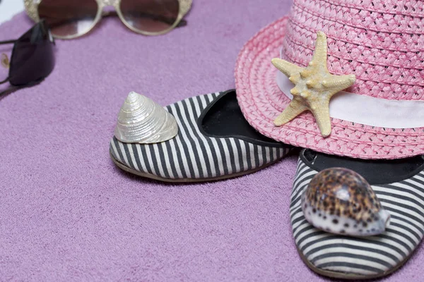 Sahilde tatile. Güneş ve güneş gözlüğü koruma için şapka. Plaj Spor Ayakkabı, deniz yıldızı. Plaj havlusu arka planı.