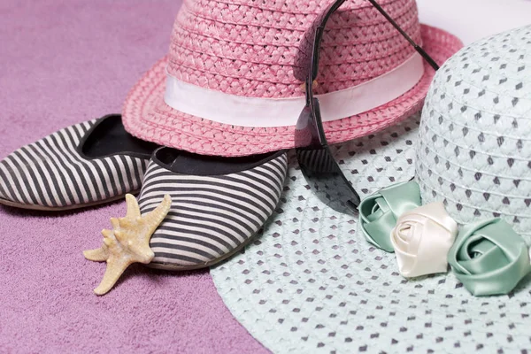 Sahilde tatile. Güneş ve güneş gözlüğü koruma için şapka. Plaj Spor Ayakkabı, deniz yıldızı. Plaj havlusu arka planı.