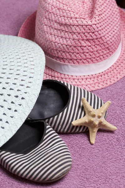 Sahilde tatile. Güneşten korunması için şapka. Plaj Spor Ayakkabı, deniz yıldızı. Plaj havlusu arka planı.