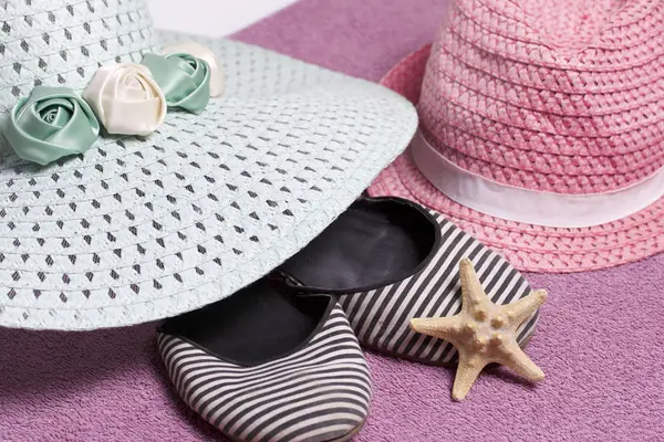 Sahilde tatile. Güneşten korunması için şapka. Plaj Spor Ayakkabı, deniz yıldızı. Plaj havlusu arka planı.