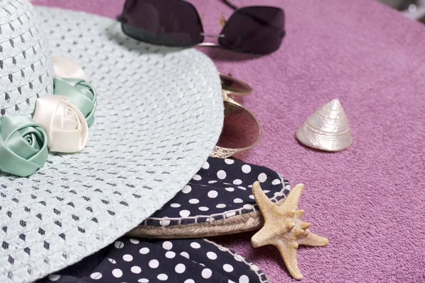 Sahilde tatile. Güneş ve güneş gözlüğü koruma için şapka. Plaj spor ayakkabıları. Deniz yıldızı ve deniz kabuklarını. Plaj havlusu arka planı.
