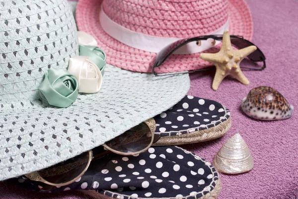 Sahilde tatile. Güneş ve güneş gözlüğü koruma için şapka. Plaj spor ayakkabıları. Deniz yıldızı ve deniz kabuklarını. Plaj havlusu arka planı.