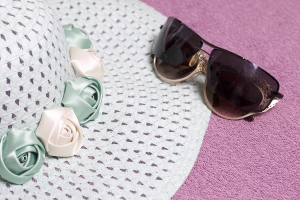 Sahilde tatile. Güneş ve güneş gözlüğü koruma için şapka. Plaj havlusu arka planı.