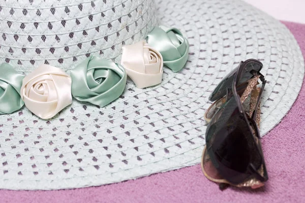 Sahilde tatile. Güneş ve güneş gözlüğü koruma için şapka. Plaj havlusu arka planı.