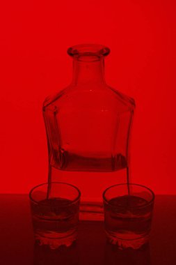 Alkollü içecek bir cam şişe. Yakınlarda bir içkiyle bardaklar.