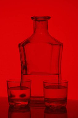 Alkollü içecek bir cam şişe. Yakınlarda bir içkiyle bardaklar.