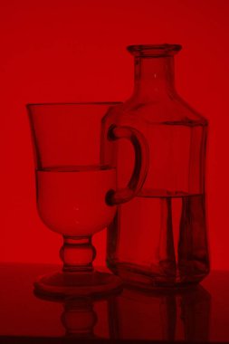 Alkollü içecek bir cam şişe. Yakınlarda bir içkiyle bardaklar.