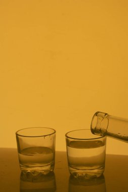 Cam kadeh içinde alkollü içecek. Bir içki şişesinden içine dökülür.