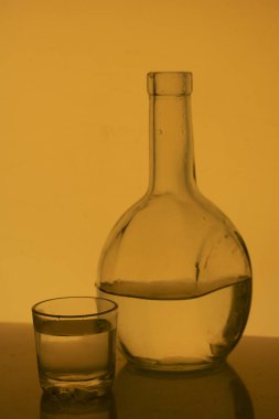 Alkollü içecek bir cam şişe. Yakınlarda bir içkiyle bardaklar.