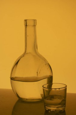 Alkollü içecek bir cam şişe. Yakınlarda bir içkiyle bardaklar.