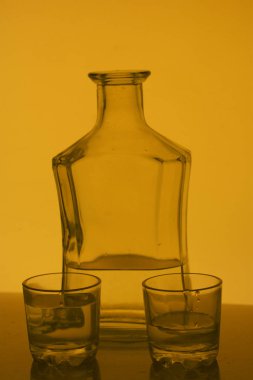 Alkollü içecek bir cam şişe. Yakınlarda bir içkiyle bardaklar.
