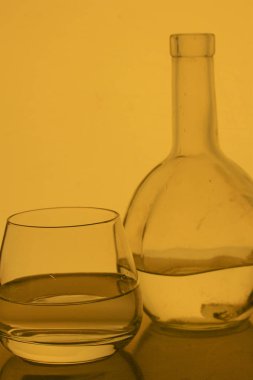 Cam kadeh içinde alkollü içecek. Yakınlarda bir şişe içki.