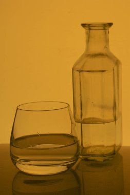 Cam kadeh içinde alkollü içecek. Yakınlarda bir şişe içki.