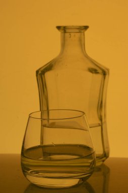 Cam kadeh içinde alkollü içecek. Yakınlarda bir şişe içki.