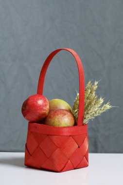 Elma sonbahar hasat. Bir hasır asma sepetten elma. Yakındaki spikelets tahıl. Gri bir arka plan üzerinde.