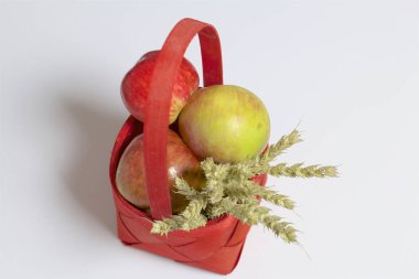 Elma sonbahar hasat. Bir hasır asma sepetten elma. Yakındaki spikelets tahıl. Beyaz bir arka plan üzerinde.