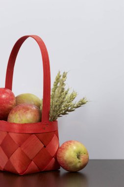 Elma sonbahar hasat. Bir hasır asma sepetten elma. Yakındaki spikelets tahıl. Beyaz bir arka plan üzerinde.