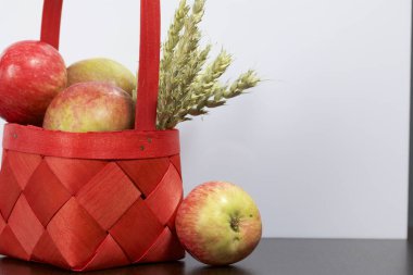 Elma sonbahar hasat. Bir hasır asma sepetten elma. Yakındaki spikelets tahıl. Beyaz bir arka plan üzerinde.