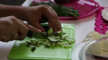 Bir adam bir salatalık bir plaka alır ve bir kesme tahtası üzerinde kesme başlar. Yakındaki içinde yemekler yemek pişirmek için diğer unsurlarıdır: tavuk yumurta ve dereotu. Yakın çekim