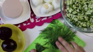Bir adam bir kesme tahtası üzerinde rezene keser. Yakındaki içinde yemekler yemek pişirmek için diğer unsurlarıdır: şeker pancarı, tavuk yumurta, sosis ve salatalık. Yukarıdan görüntülemek.