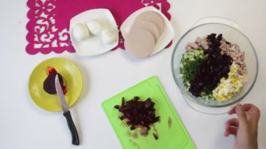 Aşçı konteyner içine haşlanmış pancar kesme tahtası üzerinden dökülen. Yakındaki içinde bulaşıkları şeker pancarı, tavuk yumurta, sosis ve salatalık yemek pişirmek için diğer unsurlarıdır. Yukarıdan görüntülemek.