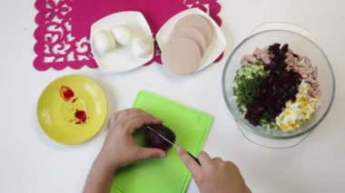 Aşçı haşlanmış pancar bir kesme tahtası üzerinde keser. Yakındaki içinde bulaşıkları şeker pancarı, tavuk yumurta, sosis ve salatalık yemek pişirmek için diğer unsurlarıdır. Yukarıdan görüntülemek
