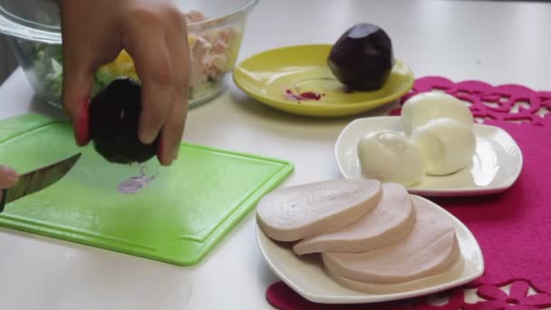 厨师把煮过的甜菜切在一个切割板上 旁边的盘子里还有烹调甜菜 鸡肉蛋 香肠和黄瓜的其他配料 — 图库视频影像